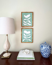 Load image into Gallery viewer, Decorative items including a lamp, books, and a vase on a table with a set of green and white botanicals in the background.