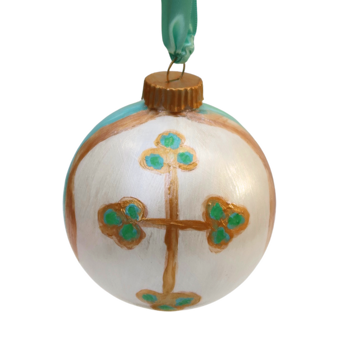 An original hand painted cross on a white ornament. The gold cross has dots of green and blue on the ends. The abstract design features blues, white, green and gold with a gold top and a green ribbon.