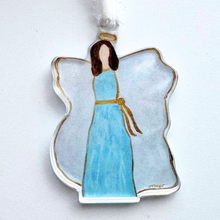 Load image into Gallery viewer, An angel ornament that is made of acrylic. It has an angel wearing blue with a gold sash, brown hair, gold halo, white wings outlined in gold.  It has a three dimensional look and the image is visible from both sides.