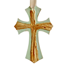 Load image into Gallery viewer, The Green Cross Ornament is an original work of art. This small cross is gold and has a raised texture. It is on a green background that is also the shape of a cross and has a cream riboon.
