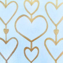 Load image into Gallery viewer, Heartstrings XII Liner for the 12 x 12 inch Acrylic Tray.  This liner insert has 3 rows of hearts. They are attached by a gold line and each heart is outlined in gold. This is a white on cream pattern. With 2 smaller gold hearts in bwtween.This liner can also be used as a placemat.

