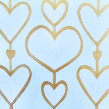 Load image into Gallery viewer, Heartstrings XII Liner for the 12 x 12 inch Acrylic Tray. This liner insert has 3 rows of hearts. They are attached by a gold line and each heart is outlined in gold. This is a white on cream pattern. With 2 smaller gold hearts in bwtween.This liner can also be used as a placemat.
