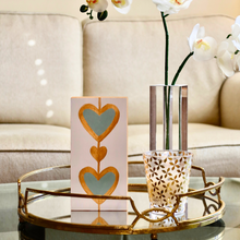 Load image into Gallery viewer, Bold Heart Original Art. This small vertical painting has two green hearts outlined in gold with a gold heart between them. It is on a white background with gold sides.