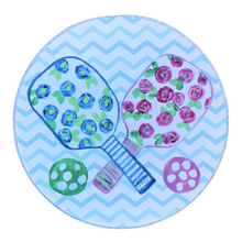 Load image into Gallery viewer, The pickleball coaster set is a preppy design on an acrylic coaster. It has 2 paddles with blue and pink flowers, green leaves on a white backgorund with striped handles and a green and pink ball. The background is a blue and white chevron pattern. It is a round acrylic coaster.
