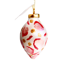 Load image into Gallery viewer, This is an animal print ornament with a gold top. It has shades of pink and red with gold dots. It has a white ribbon for hanging.