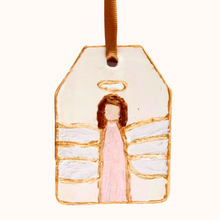 Load image into Gallery viewer, The Pink angel ornament is an original hand painted angel on a ceramic ornament. The background is cream. The angel has a pink dress, white wings, brown hair and a gold halo. The angel is outlined in gold and the ornament is outlined in gold. It has a gold ribbon for hanging.