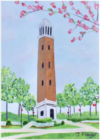 Denny Chimes Acrylic Block Art. This Alabama Crimson Tide free standing acrylic block art is vertical and features the famous Bell Tower landmark that is in The Quad at The University of Alabama. This is a print on an acrylic block of a bell tower with flowering trees and plants. Roll Tide!