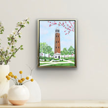 Load image into Gallery viewer, Alabama campus art featuring Denny Chimes in Tuscaloosa with blooming spring branches, landscaped pathways, and elegant gold framing perfect for Crimson Tide fans and alumni.
