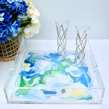 Load image into Gallery viewer, Acrylic Tray with a coastal inpsired interchangeable liner. This tray measures 12 x 12 inches. The abstract image has shades of blue, white, green and yellow. It is styled with 2 champagne glasses and a vase of hydrangeas. 
