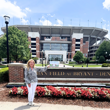 Load image into Gallery viewer, Colorful fine art print of Bryant-Denny Stadium featuring crimson flags, Alabama football details, green trees, and a landscaped flower bed.