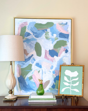Load image into Gallery viewer, Grandmillennial style table top setup colorful abstract art, lamp, and green vase on a table and a green and white floral painting;.