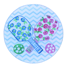 Load image into Gallery viewer, The pickleball coaster set is a preppy design on an acrylic coaster. It has 2 paddles with blue and pink flowers, green leaves on a white backgorund with striped handles and a green and pink ball. The background is a blue and white chevron pattern. It is a round acrylic coaster.
