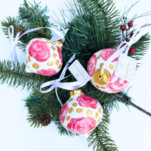 Load image into Gallery viewer, Pink and gold ceramic holiday ornament displayed on a Christmas tree with feminine floral artwork.
One-of-a-kind hand-painted ceramic ornament in blush pink, rose, white, and metallic gold for Christmas decorating.
Elegant pink floral Christmas ornament signed by artist Jeanne Player and ready for holiday gifting.