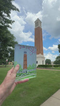 Load and play video in Gallery viewer, Denny Chimes Bell Tower at The University of Alabama. This is an original work of art reproduced onto a clear acrylic block. It is a red brick building with a white top and bottom. It sits in a green park space with sidewalks, shrubbery and flowers around it.
