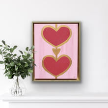 Load image into Gallery viewer, Contemporary heart artwork featuring two red hearts outlined in gold on soft pink canvas.