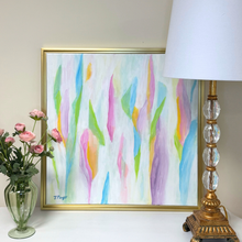 Load image into Gallery viewer, A framed abstract painting with vertical pastel brushstrokes in pink, blue, green, yellow, and purple, displayed on a tabletop beside a vase of pink roses and a white lamp with a gold base.