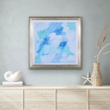 Load image into Gallery viewer, This is an abstract giclee print on paper with a white border signed by the artist. This painting has shades of blue, green and white.  It is shown in a frame over a table with seashells and a wicker vase of flowers.
