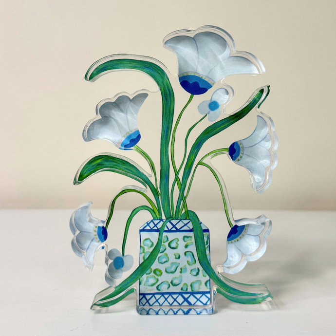Freestanding acrylic art block featuring whimsical white flowers outlined in gray with blue, pink, and lime green accents in a patterned cachepot against a light blue background. Vertical floral artwork by Jeanne Player. This is a free standing acrylic cut out shape.