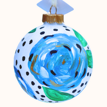 Load image into Gallery viewer, A fun and whimsical blue floral ornament. This round abstract floral has shades of blue, white ,black and gold with green leaves. This original hand painted ornament is round an has a black dot s on a white background.
