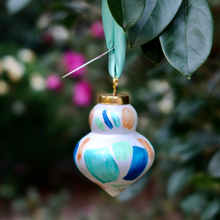 Load image into Gallery viewer, Coastal abstract Christmas ornament with shades of teal, green, blue, white and gold.  Signed on the bottom and adorned with an aqua satin ribbon, each ornament is one-of-a-kind, so expect charming variations.
