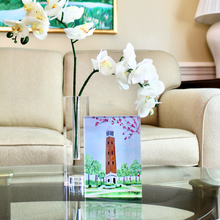 Load image into Gallery viewer, Denny Chimes Acrylic Block Art. This Alabama Crimson Tide free standing acrylic block art is vertical and features the famous Bell Tower landmark that is in The Quad at The University of Alabama. This is a print on an acrylic block of a bell tower with  flowering trees and plants. Roll Tide!
