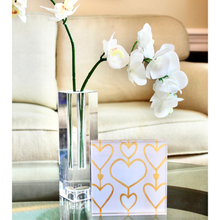 Load image into Gallery viewer,  Heart Art. A 5.5 inch free standing acryic block  that has the image of hearts on the background. They are 3 rows of white hearts on a cream background outlined in gold  connected by a gold line. This shelf sitter is styled on a mirrored tray beside a clear glass vase holding white orchids. This is a copy of the Heartstrings XIi painting make into an acrylic block. 
