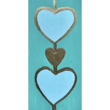Load image into Gallery viewer, An original heart art painting. This painting has two blue hearts outlined in gold with a gold heart between them on a green background. It is a vertical painting.
