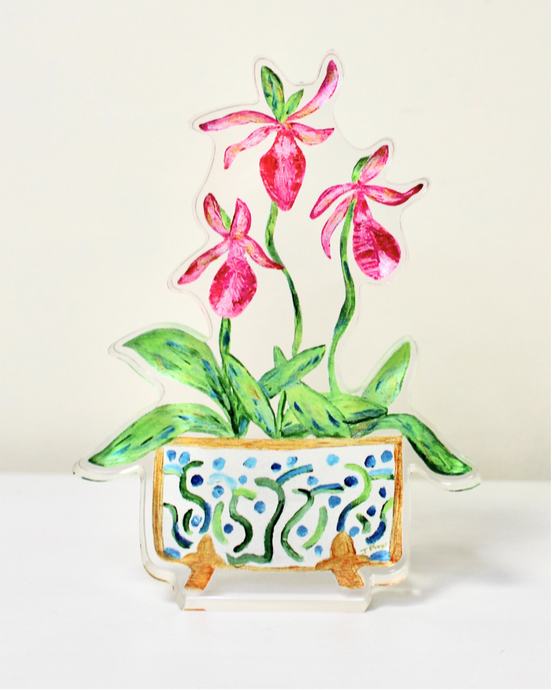 The Ladyslipper Freestanding Acrylic Block is a colorful artwork in acrylic. This cutout acrylic block art has three pink orchid blooms, green leaves in a beautiful cachepot with a fun design in blue and green on a white background with gold feet and outlined in gold.