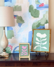 Load image into Gallery viewer, Traditional Decorative table top with lamp, green and white floral artwork, green and pink floral painting and colorful abstract painting.
