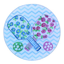 Load image into Gallery viewer, The pickleball coaster set is a preppy design on an acrylic coaster. It has 2 paddles with blue and pink flowers, green leaves on a white backgorund with striped handles and a green and pink ball. The background is a blue and white chevron pattern. It is a round acrylic coaster.
