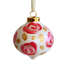 Load image into Gallery viewer, This is an abstract floral art design ornament. It has flowers in shades of pink and red  with gold dots in between them on a white background. It has a gold top and a white ribbon.
