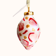 Load image into Gallery viewer, This is an animal print ornament with a gold top. It has shades of pink and red with gold dots. It has a cream raw silk  ribbon for hanging.

