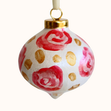 Load image into Gallery viewer, This is an abstract floral art design ornament. It has flowers in shades of pink and red with gold dots in between them on a white background. It has a gold top and a white ribbon.
