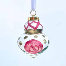 Load image into Gallery viewer, Hand-painted Christmas ornament with abstract pink and red flowers, green leaves, gold dots, and lattice detail. Finial-style round ornament with satin ribbon for hanging, whimsical and unique holiday décor.
