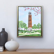 Load image into Gallery viewer, Framed Denny Chimes original artwork showcasing the famous University of Alabama landmark surrounded by flowering trees, green lawns, and winding campus walkways.
