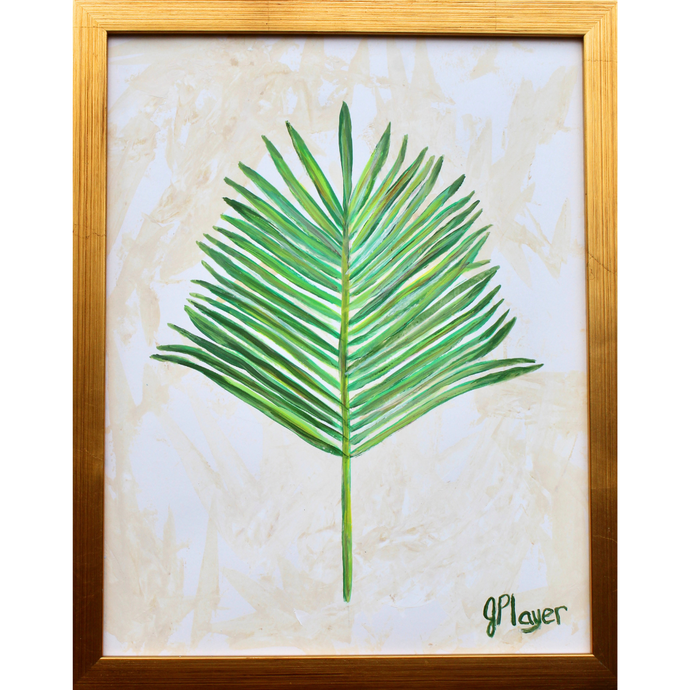 The Palm is a preppy and modern painting of a palm leaf on paper. The leaf has various shades of green with a hint of yellow. This is on a tan and white background. This vertical botanical painting is in a gold frame.