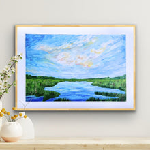 Load image into Gallery viewer, Horizontal giclée fine art print of a peaceful low country marsh at sunset, with windswept clouds in yellow, orange, pink, and blue reflecting in calm water and surrounded by lush green grasses and distant trees.
