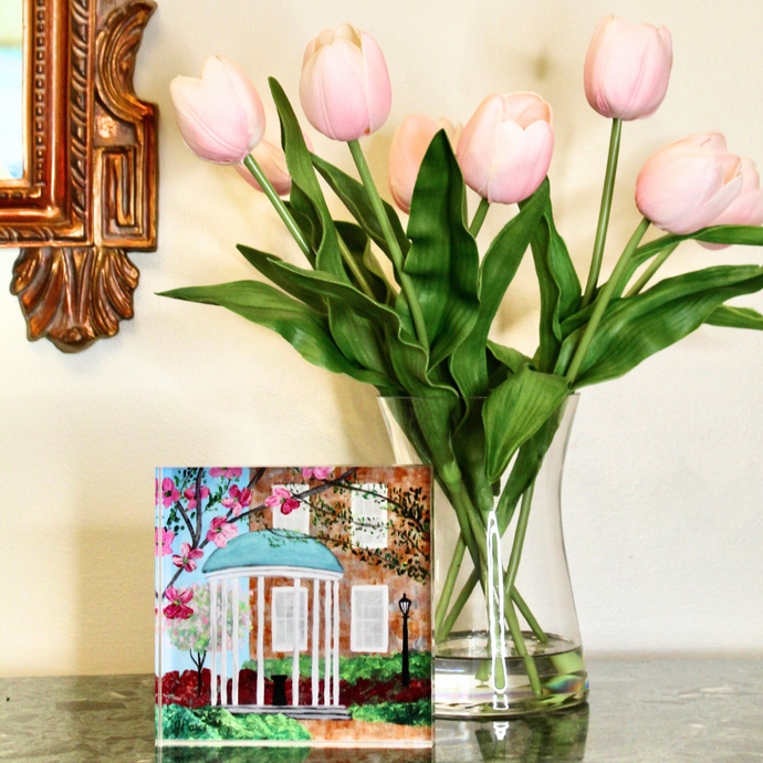 UNC Acrylic Block is an original painting repoduced on heavy weiight paper and affixed to a free standing acrylic block.  The image is visible from all 4 sides. This mini artwork is displayed on a table with a vase of pink tulips.