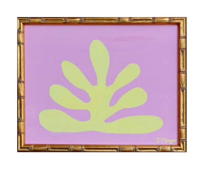 This is a bold and preppy seaweed art design on a canvas. This painting has a yellow seaweed shape on a pink background. This is a horizontal painting in a gold bamboo frame.