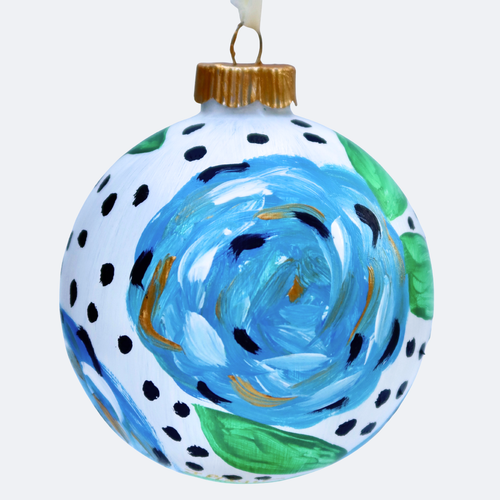 A Christmas tree ornament with a hand painted blue floral design. It is an original work of art painted onto a round Christmas ornament. It has shades of blue, white, green, black and gold. It comes with a satin ribbon for hanging. it has black dots in between the flowers.