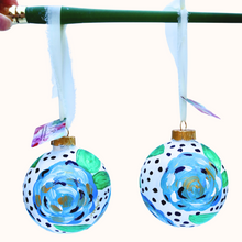 Load image into Gallery viewer, Hand-painted blue floral Christmas ornament featuring abstract blue and white flowers with metallic gold accents on a black dotted background.
Original 4-inch shatterproof Christmas ornament with blue floral artwork, green leaves, and a cream raw silk ribbon.
