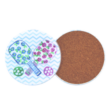 Load image into Gallery viewer, Back of a round pickleball acrylic coaster showing the cork backing designed to protect tabletops. Round pickleball acrylic coaster featuring pink and blue floral paddle artwork and a colorful chevron background
