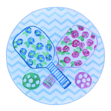 Load image into Gallery viewer, The pickleball coaster set is a preppy design on an acrylic coaster. It has 2 paddles with blue and pink flowers, green leaves on a white backgorund with striped handles and a green and pink ball. The background is a blue and white chevron pattern. It is a round acrylic coaster.
