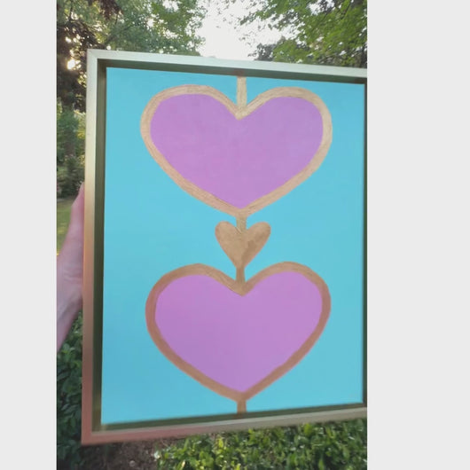 A colorful heart painting with 2 pink hearts a gold heart on an aqua green background in a gold frame. This is a small painting measuring 11 x 14 inches. It would be perfect in a girls bedroom.