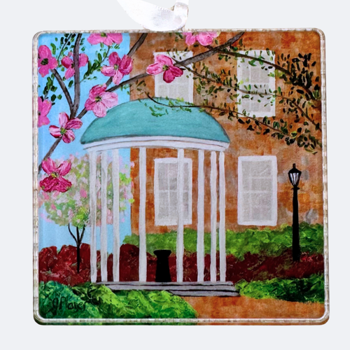 The UNC Old Well at the University of North Carolina Christmas Ornament. This is an acrylic ornament that is square and made of lightweight acrylic.  It has shades of blue, white, gray, black, red and pink. and green.  It features the landmark of the old well at UNC Chapel Hill.
