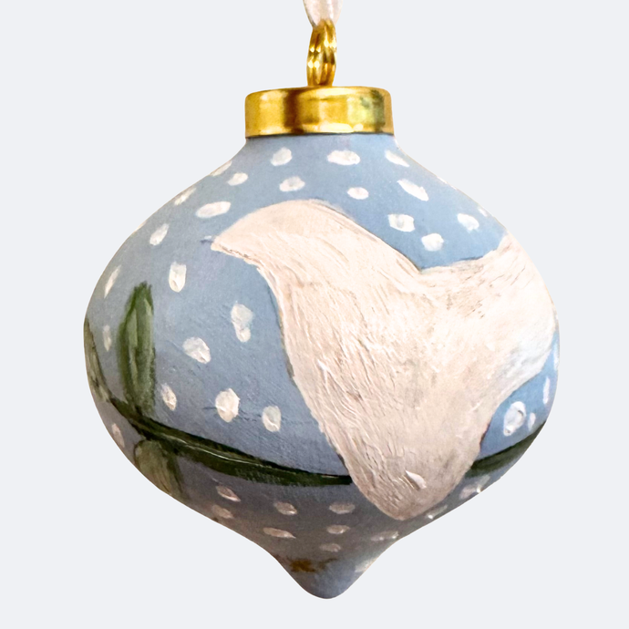 a hand painted christmas tree ornament made of ceramic. This ornament has a white dove with a green leaves  on a blue background with white dots. It is on a round tear shaped ornament. it is hand painted and unique.